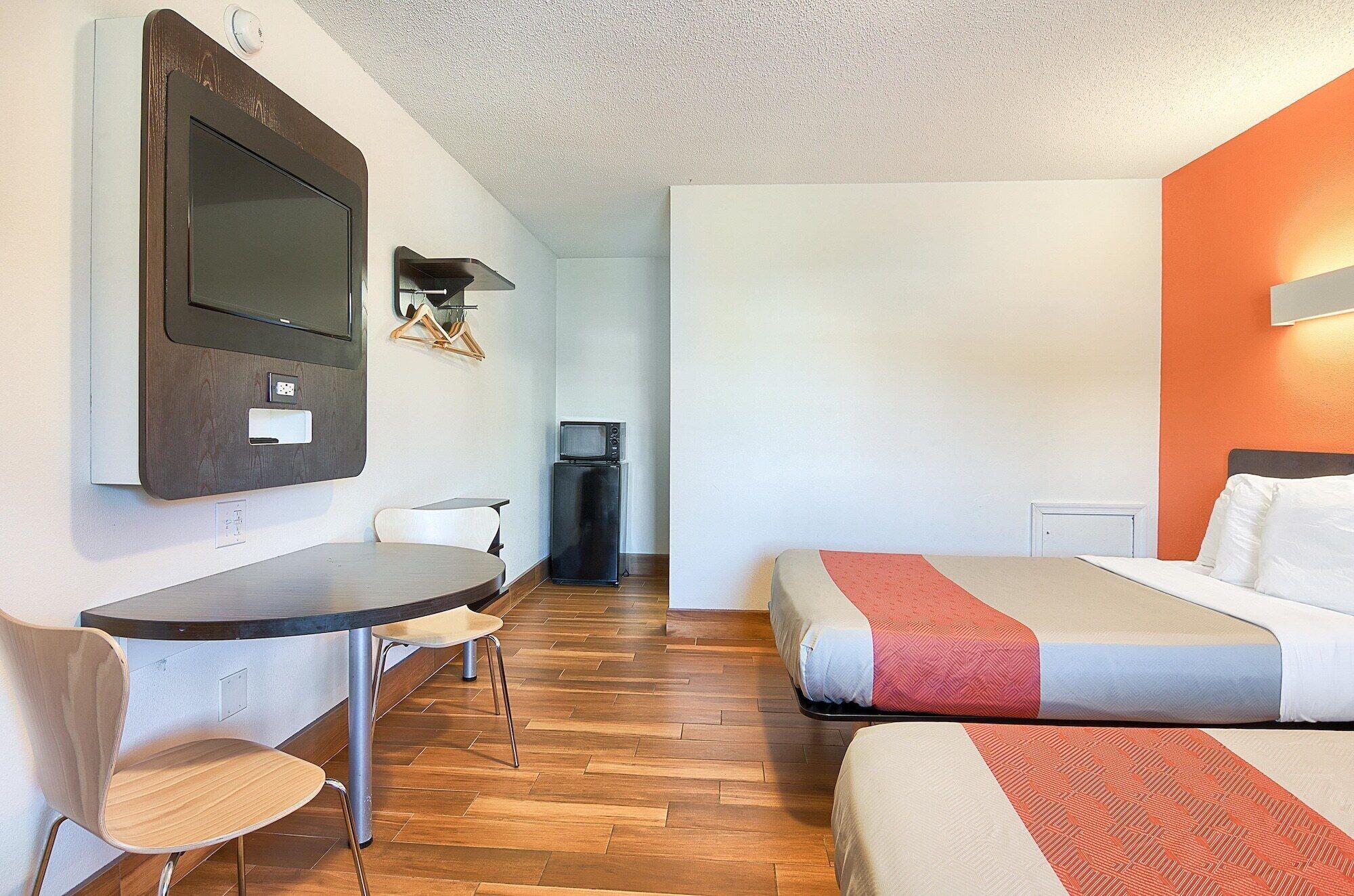 Ein Hotelzimmer mit Bett, Schreibtisch, Stuhl, Fernseher und einer kleinen Küchenzeile.