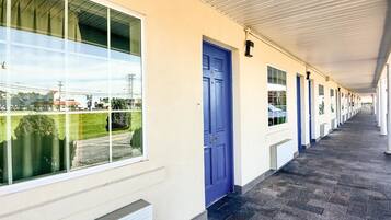 A corridor with a blue door marked with the number 55, leading to a row of rooms with windows.