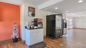 Ein Hotelzimmer mit Küchenzeile, einer Kaffeemaschine, einem Kühlschrank und einem Topf mit Pflanze.