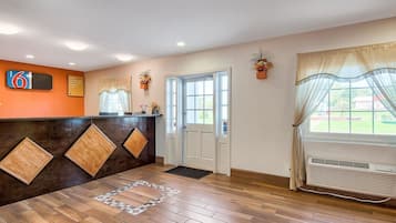 A reception area with a wooden floor, a reception desk, a door, and a window with a view of the outside.