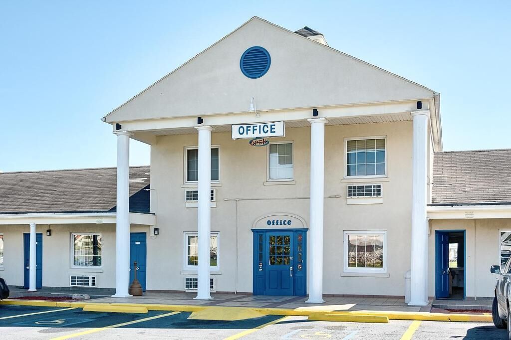 A building with a sign reading 'OFFICE' above the entrance, featuring a classic architectural style with columns and a pitched roof.