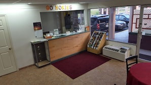 A bakery with a wooden counter, a 'GO HOKIES' sign, a window with a view of parked cars, and a red carpet. - Red Carpet Inn Blacksburg (Blacksburg)
