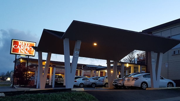 A Red Carpet Inn with a covered parking area and several cars parked. - Red Carpet Inn Blacksburg (Blacksburg)
