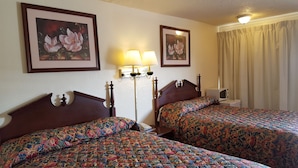 A hotel room with two beds, floral artwork on the walls, a bedside lamp, and a microwave. - Red Carpet Inn Blacksburg (Blacksburg)