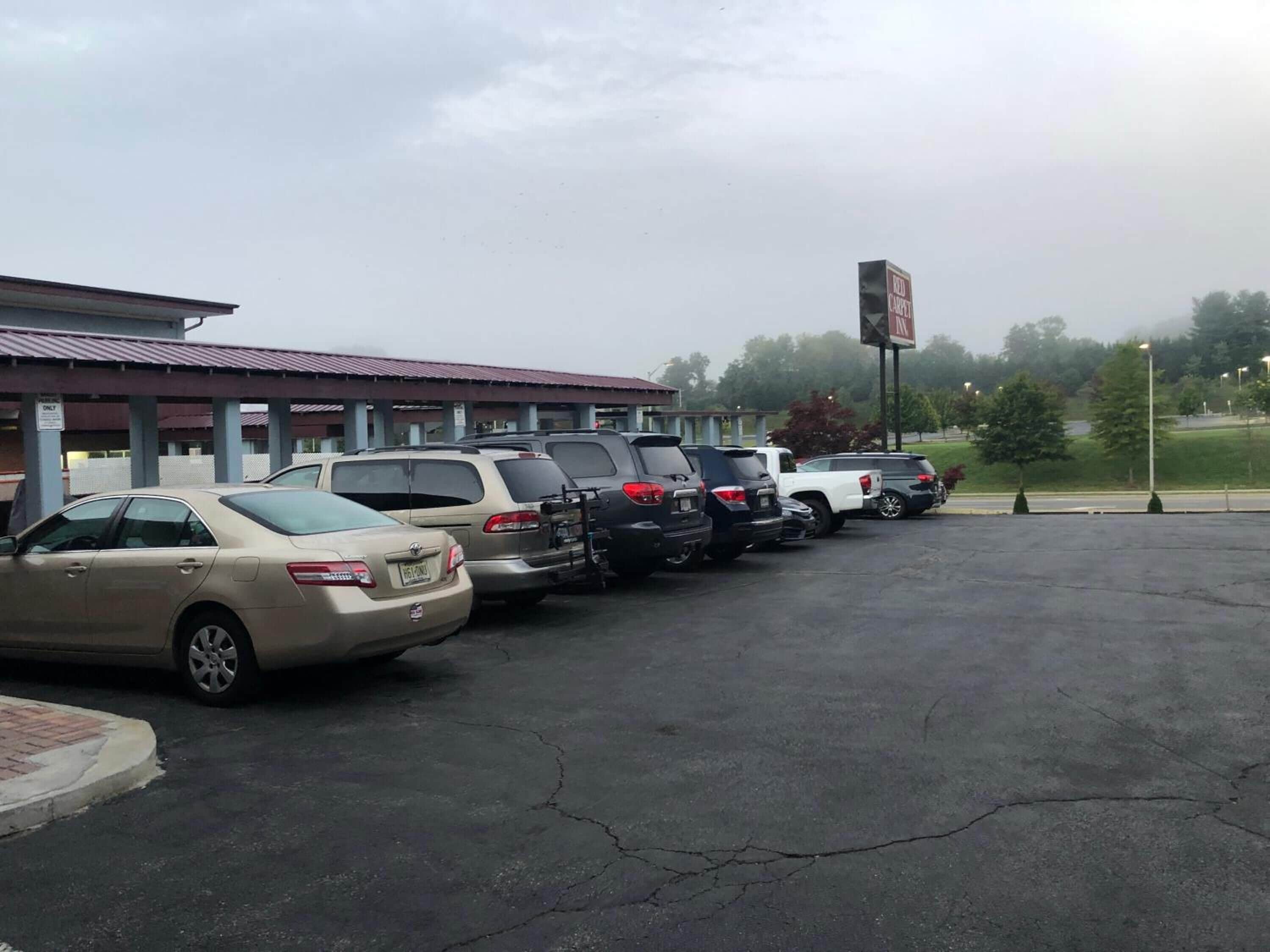 A parking lot with several cars parked in front of a building with a red roof.
