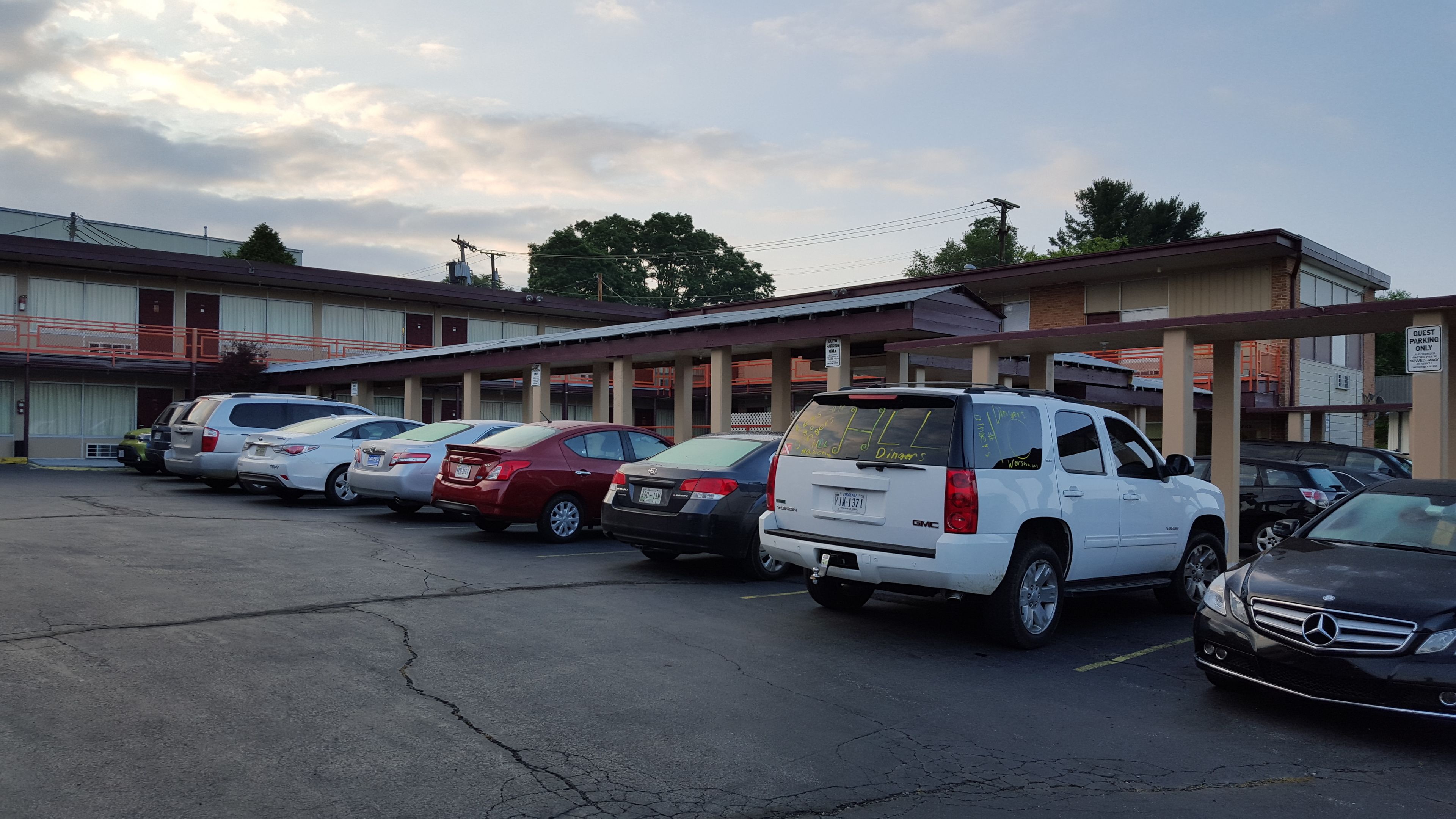 Un estacionamiento con varios autos estacionados frente a un motel, con un letrero que indica 'Solo para huéspedes'.