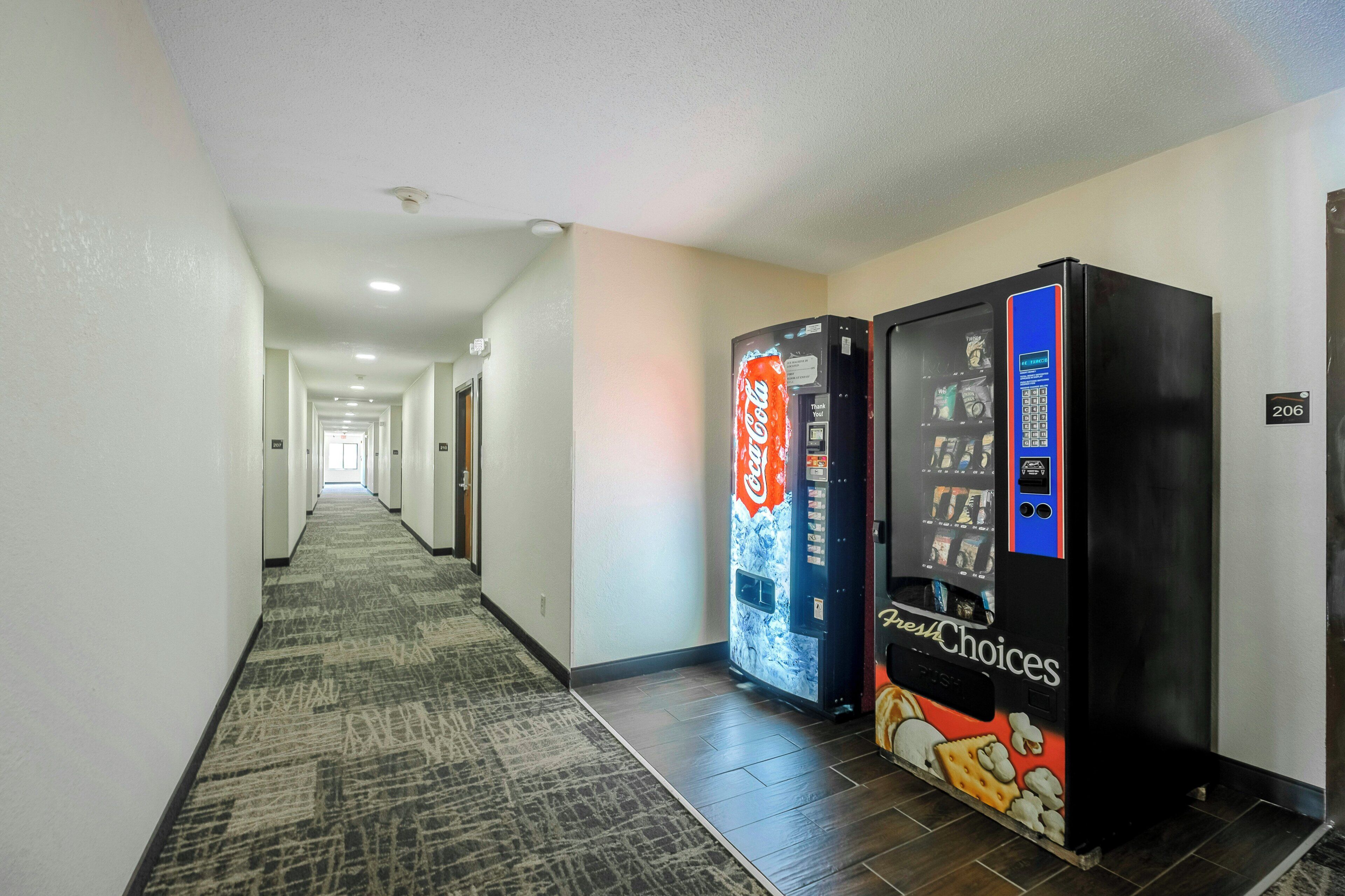 Ein Hotelkorridor mit Teppichboden, zwei Getränkeautomaten und einer Tür mit der Nummer 206.