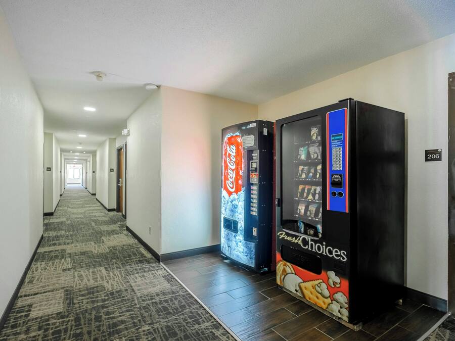 A hotel hallway with a carpeted floor, two vending machines, and a door with the number 206.