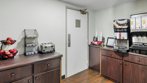 A kitchenette with a coffee maker, toaster, and fruit basket.