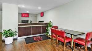 A Red Roof Inn reception area with a desk, chairs, and a potted plant.