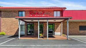 Ein Red Roof Inn mit Ziegelaußenwand, großen Fenstern und einem überdachten Eingang.