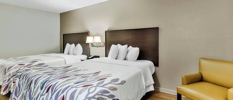 Une chambre d’hôtel avec deux lits, un canapé, une table de chevet avec des lampes et un plancher en bois.