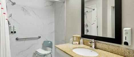 Un baño moderno con ducha, lavabo, silla y espejo.