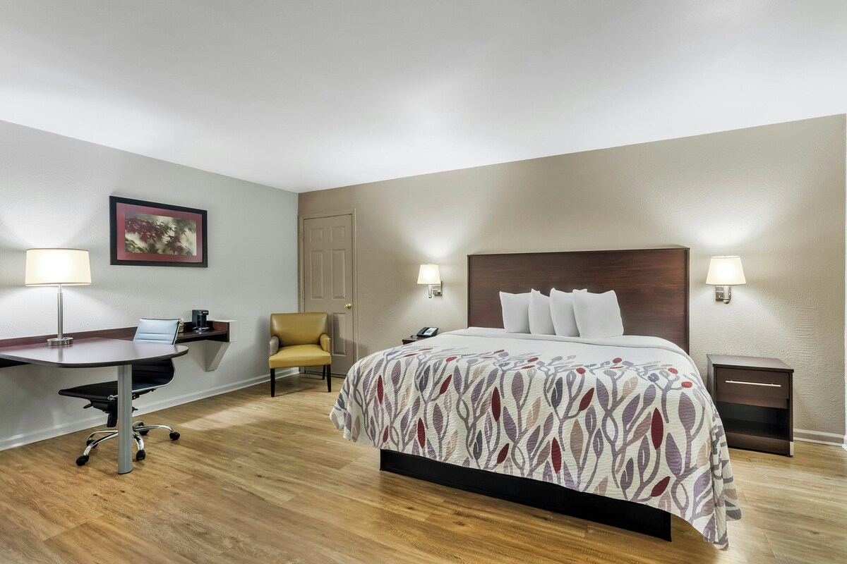Een hotelkamer met een bed, bureau, stoel en twee bedlampjes.