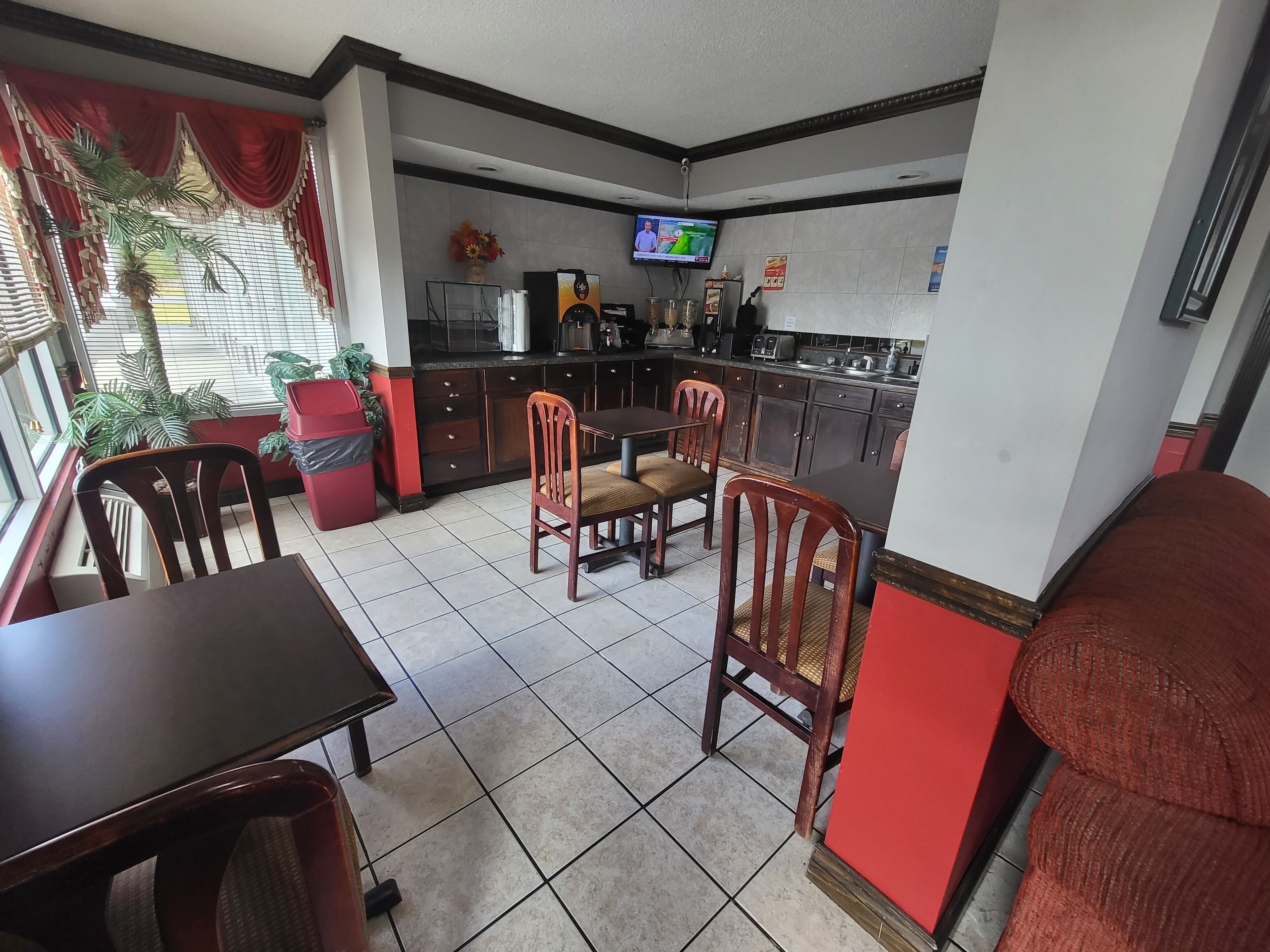 A dining area with a TV, kitchen, and red accents.