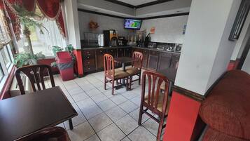 A dining area with a TV, kitchen, and red accents.