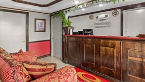 A reception area with a wooden desk, a red carpet, and a plant. - Econo Lodge Andalusia (Andalusia)