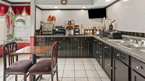 A kitchen with dark cabinets, a coffee machine, and a sink. - Econo Lodge Andalusia (Andalusia)