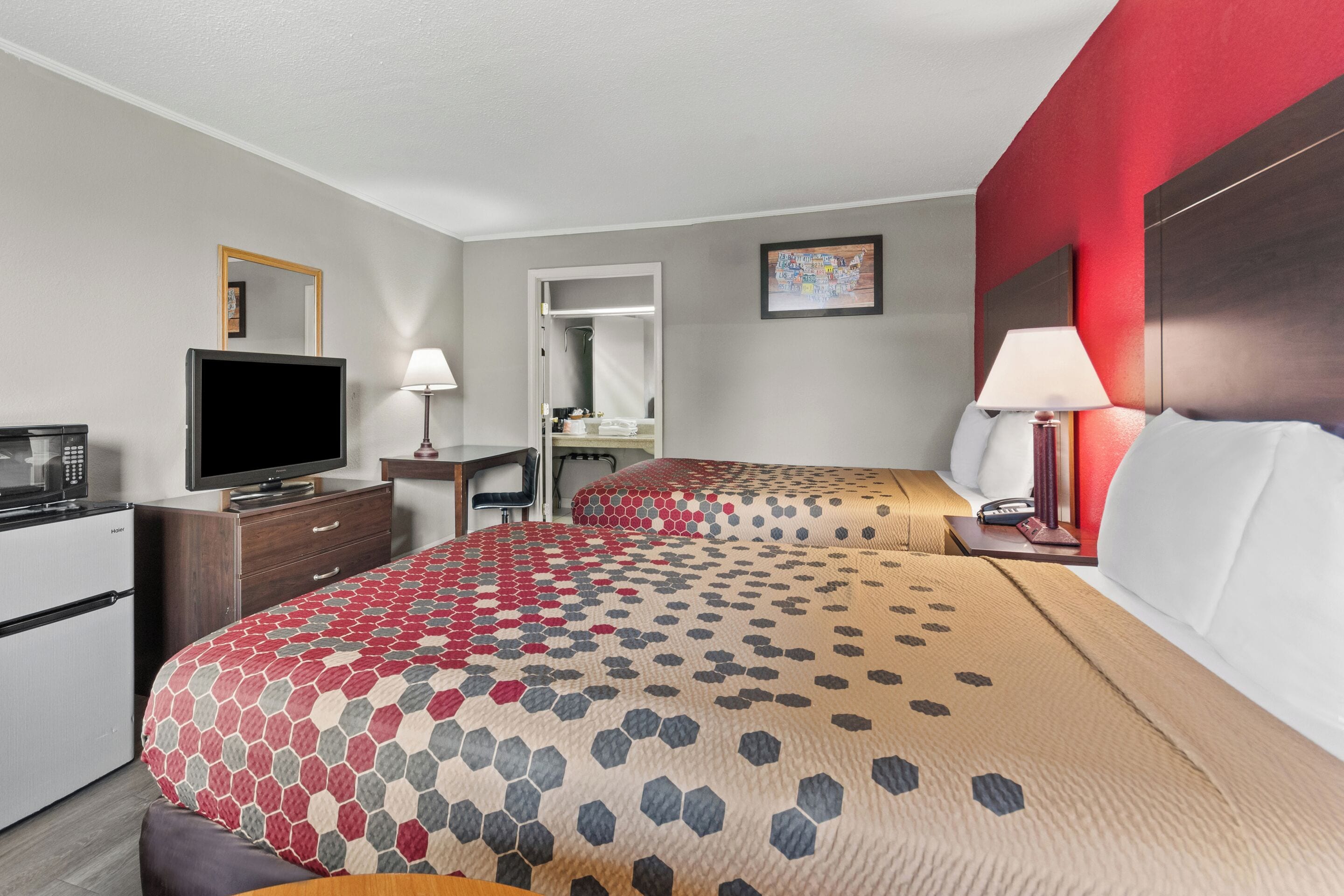 A hotel room with a bed, a desk, a television, and a refrigerator.