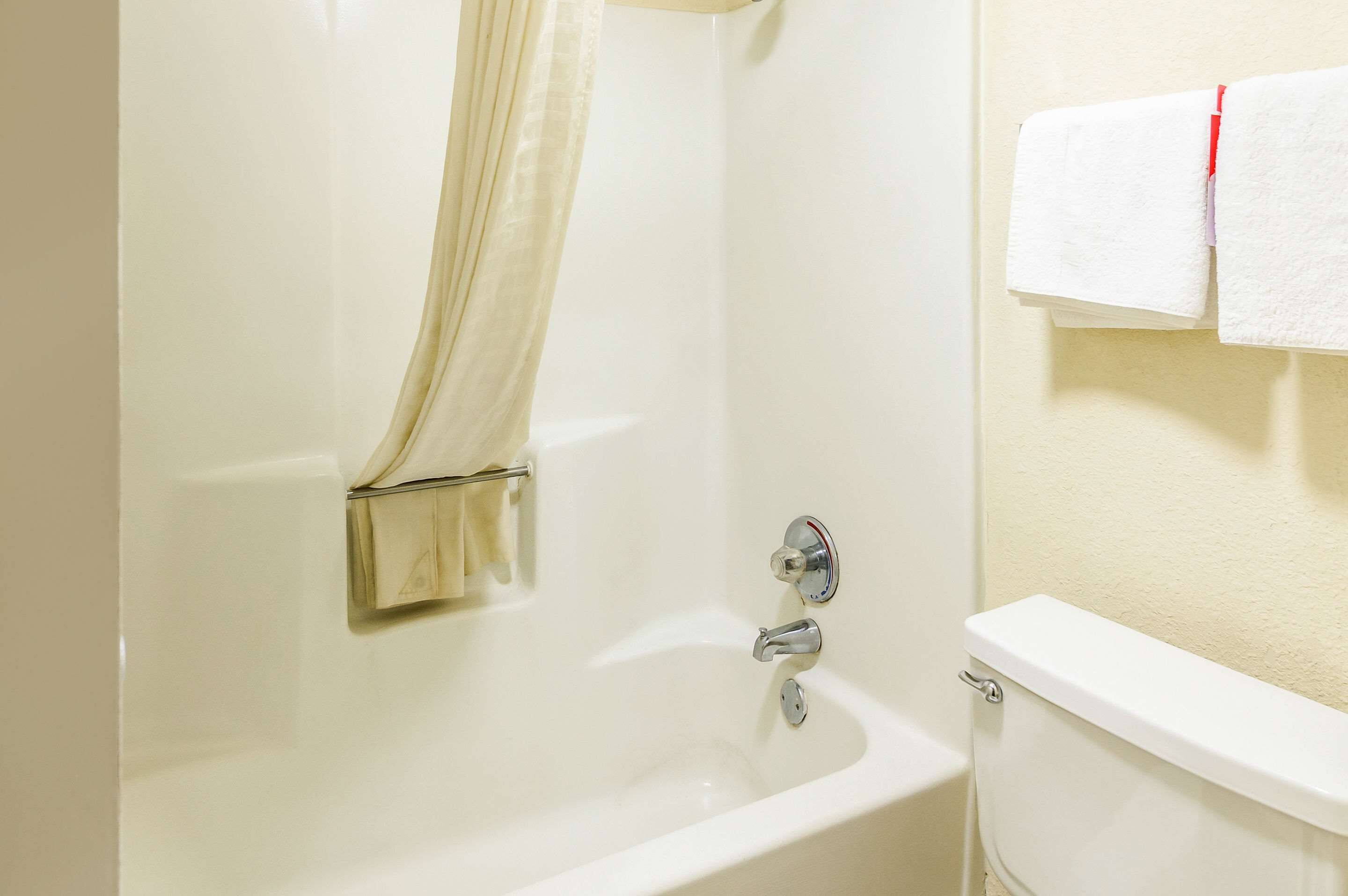 Un baño con bañera, inodoro y un perchero con toallas.