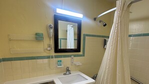 A bathroom with a white sink, a toilet, a mirror, and a shower curtain. - Super Inn (Daytona Beach)