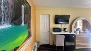 A room with a mural of a waterfall, a TV mounted on the wall, a microwave on a counter, and a refrigerator. - Super Inn (Daytona Beach)