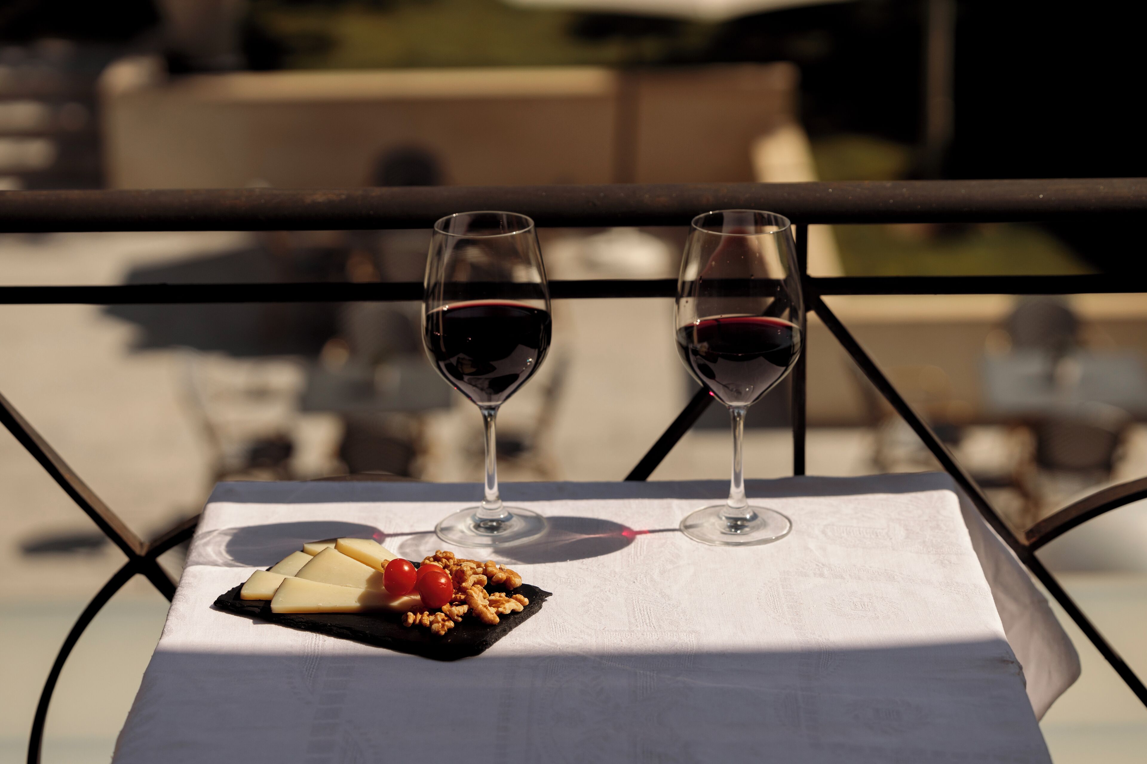 Une table avec deux verres à vin et une planche à fromages garnie de noix et de tomates cerises.