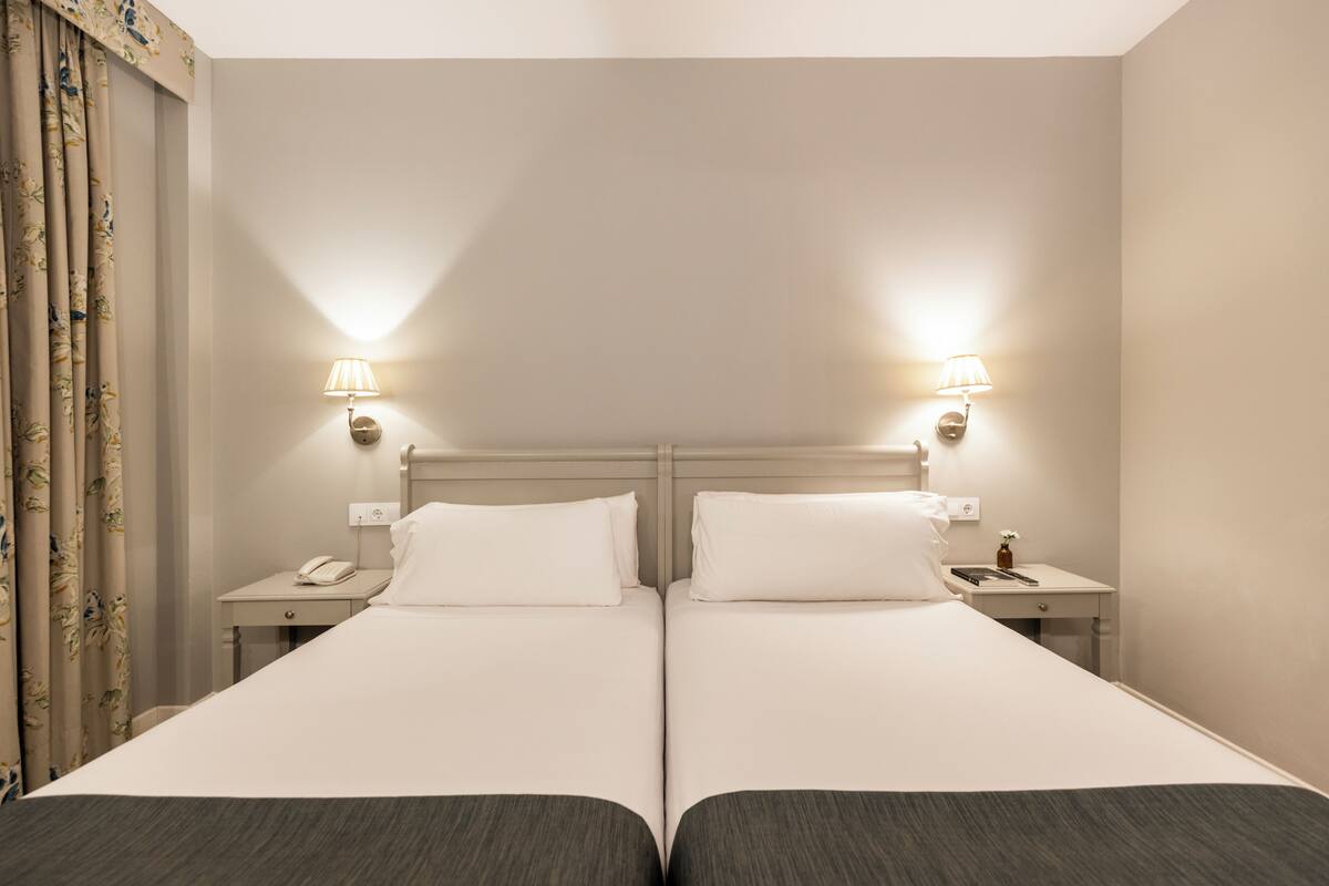 Een tweepersoonsbed met twee nachtkastjes, elk met een lamp en een telefoon.