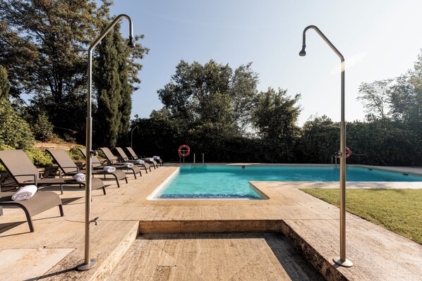 A swimming pool with lounge chairs and a hot tub area.