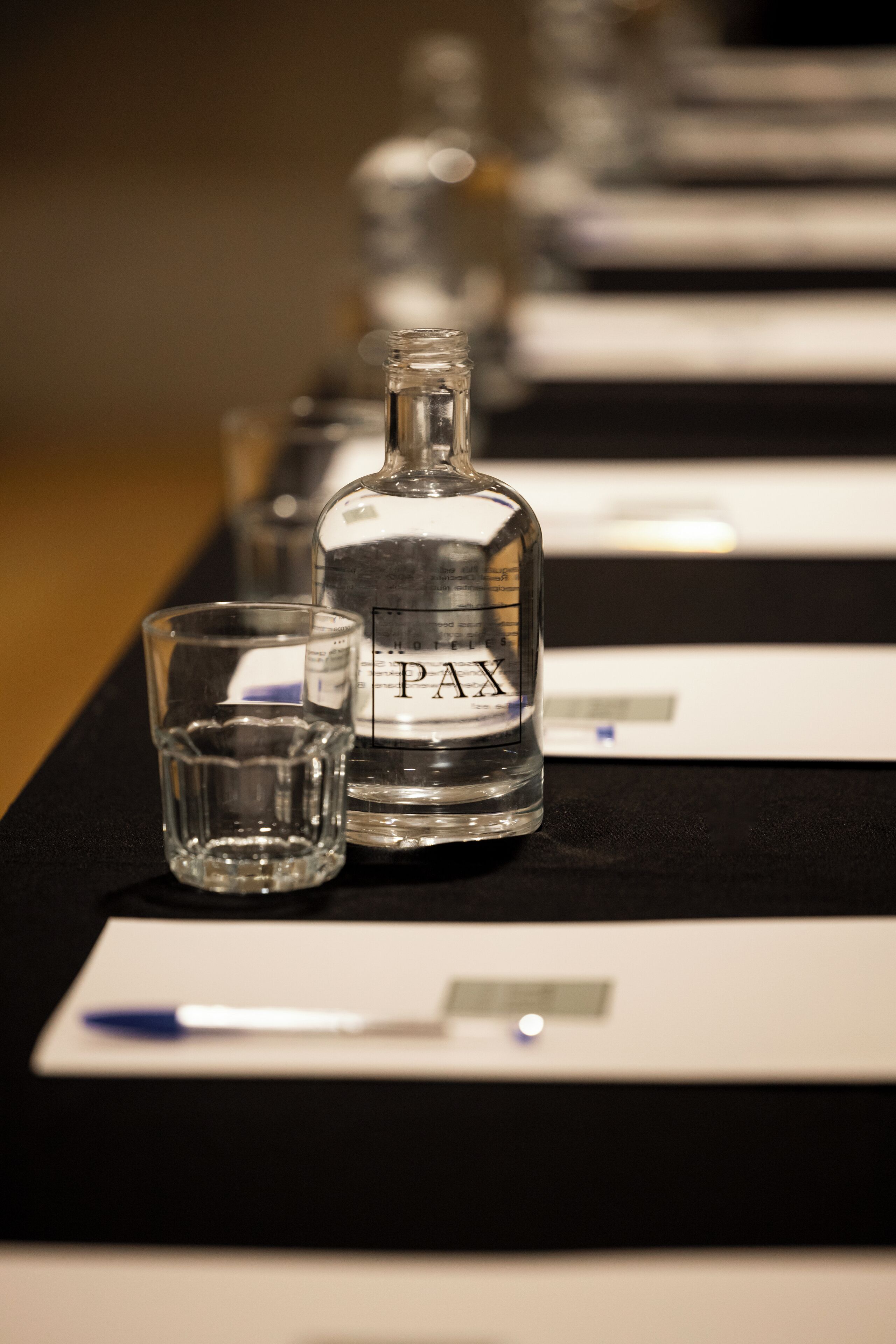 Een fles PAX en een glas op een tafel met naamkaartjes.
