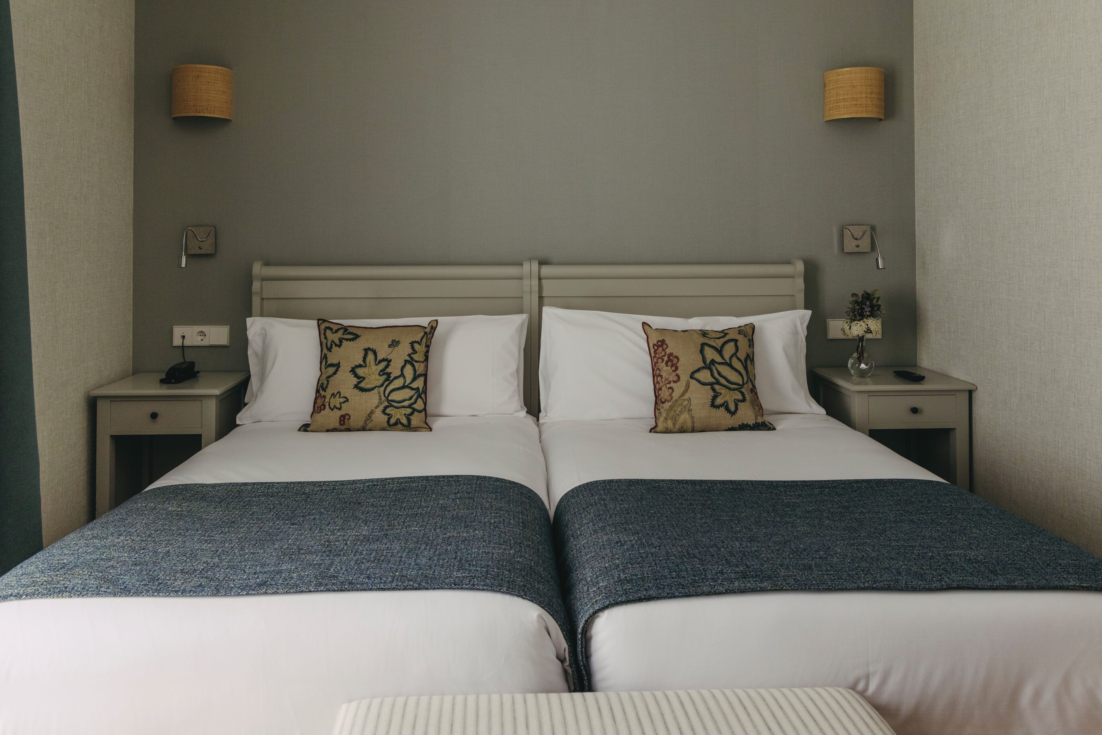 A double bed with two nightstands, each with a lamp and a clock.