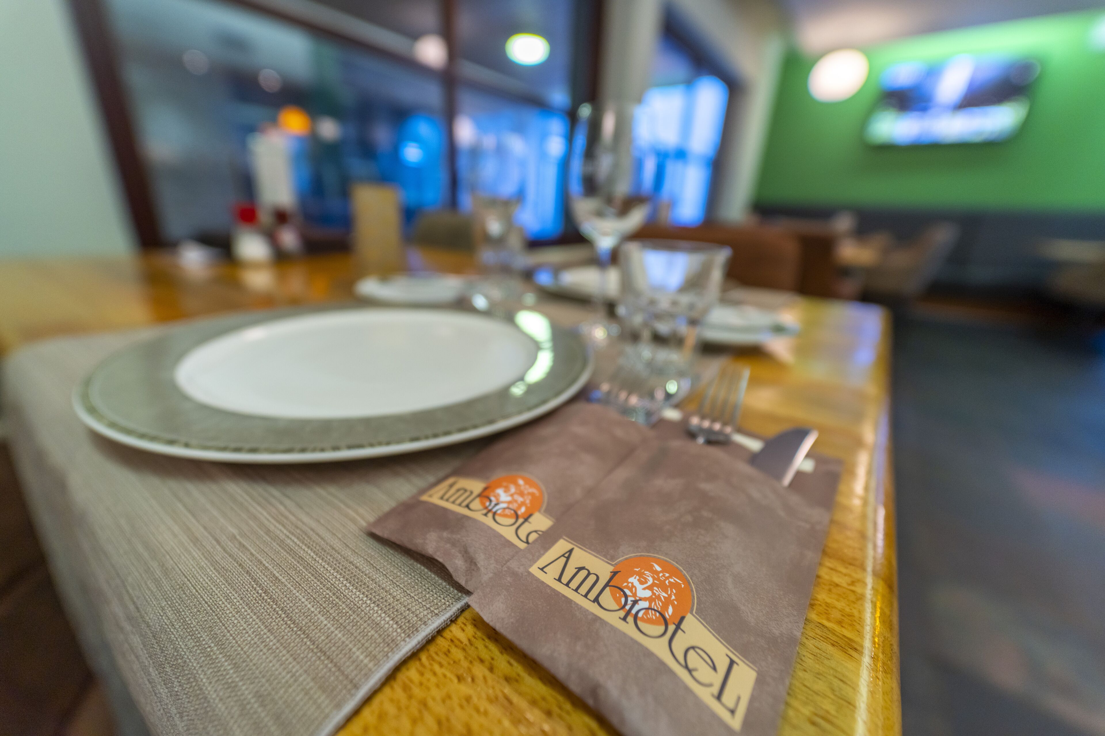 Una mesa de restaurante dispuesta con platos, cubiertos y una servilleta con un logotipo.