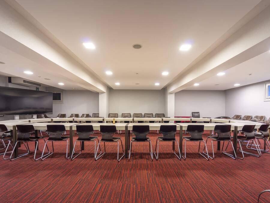 Une salle de conférence dotée d’une longue table, de nombreuses chaises, d’un grand écran et d’un éclairage encastré.