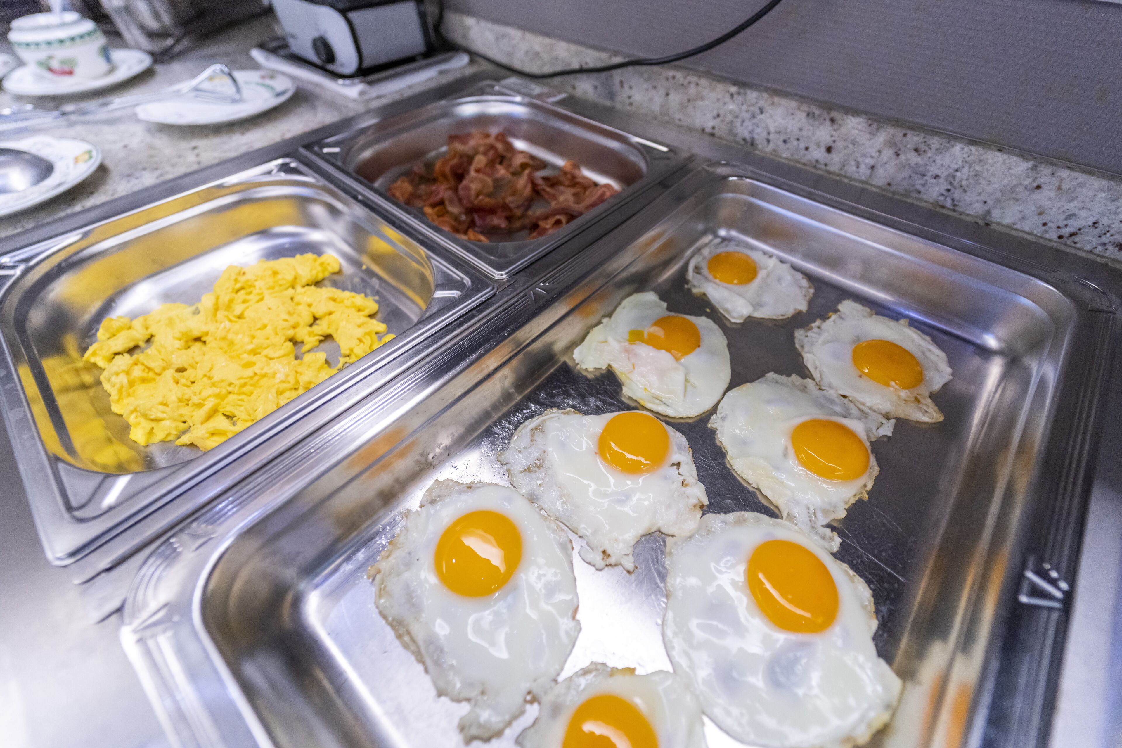 Ein Buffet mit Rührei, Spiegeleiern und Speck.