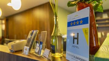 A hotel reception desk with a sign indicating it is a four-star hotel, a glass vase with a plant, and a bottle of wine.