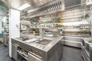 A commercial kitchen with stainless steel appliances, a large sink, and a ventilation hood. - Ambiotel (Tongeren)