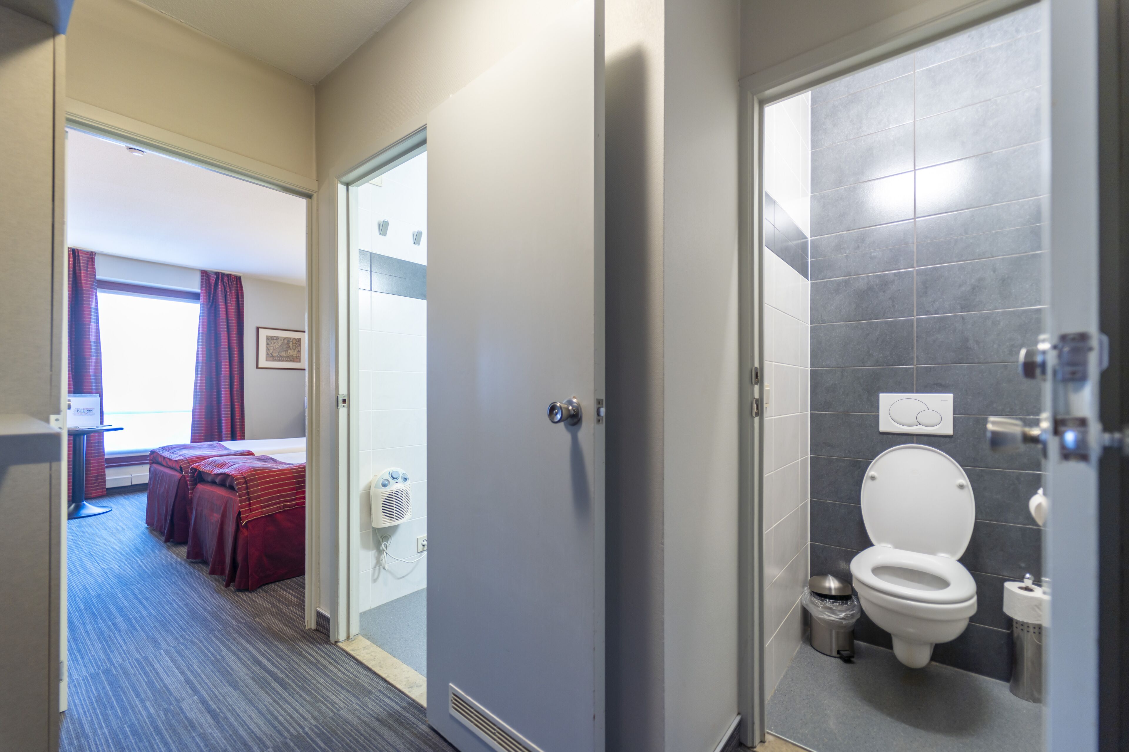 Een hotelbadkamer met een toilet, een bidet en een kleine prullenbak.