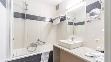 Een moderne badkamer met een bad, douche en wastafel.