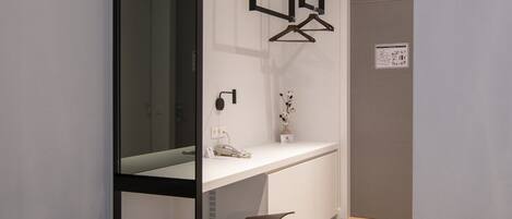 A modern hotel room with a bed, a desk, and a mirror.