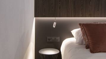 Een moderne slaapkamer met een bed, een ronde zwarte stoel, een bedieningspaneel aan de muur en een houten accentmuur.