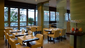 En restaurang med bord uppställda för servering, stora fönster och en glasvägg.