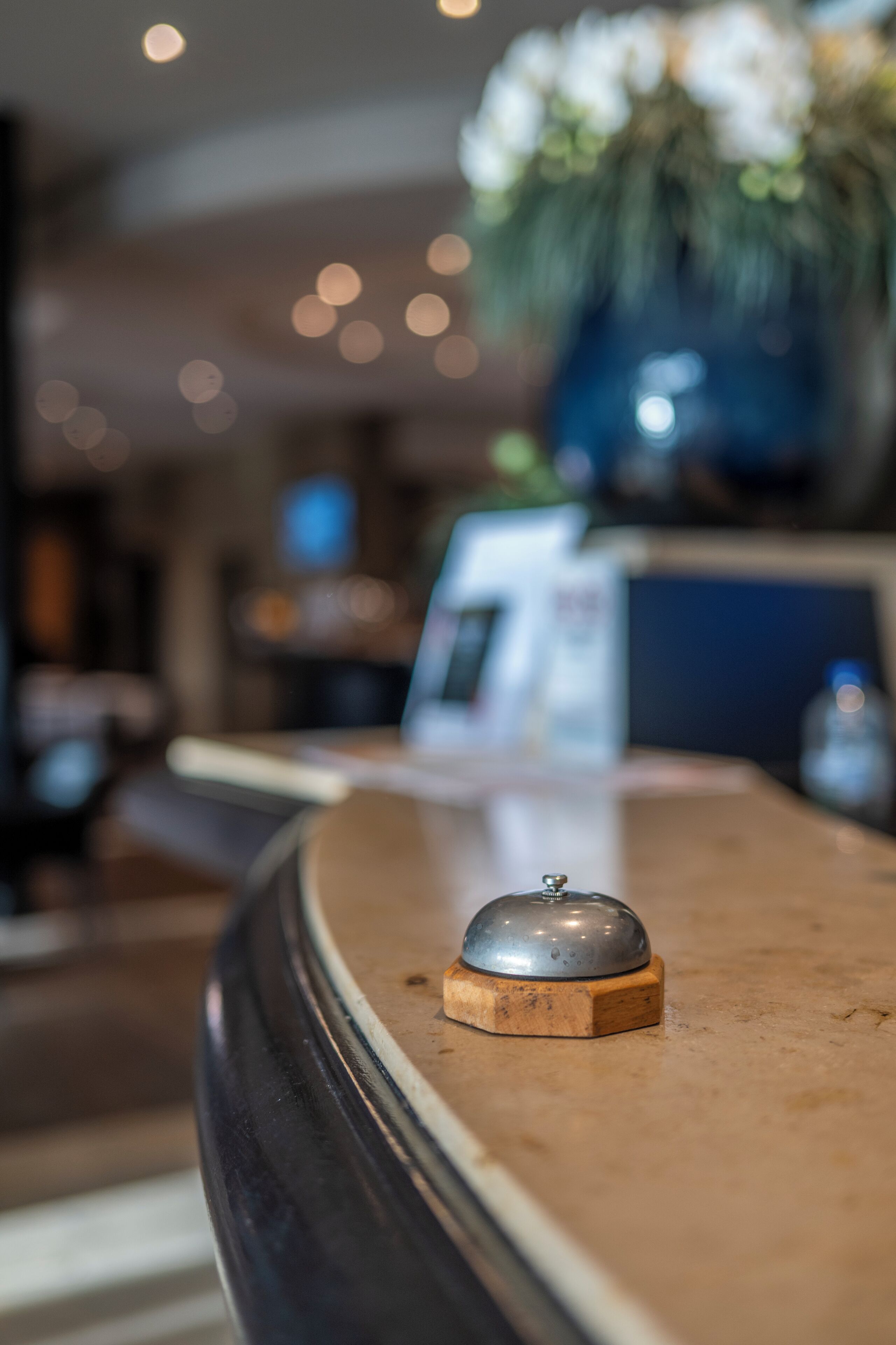 A reception desk with a wooden base and a metal bell.