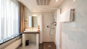 A modern bathroom with a sink, mirror, shower, and towel rack.