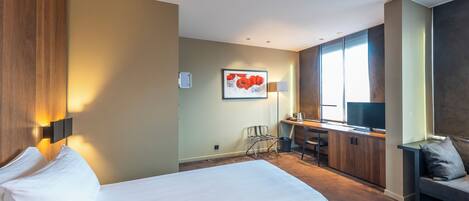 A hotel room with a bed, desk, chair, and a television.