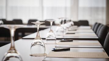 Un salón de conferencias con una larga mesa, varios vasos de vino y un bloc de notas.