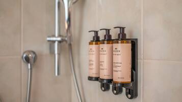 A bathroom with a wall-mounted shampoo dispenser and a shower head.
