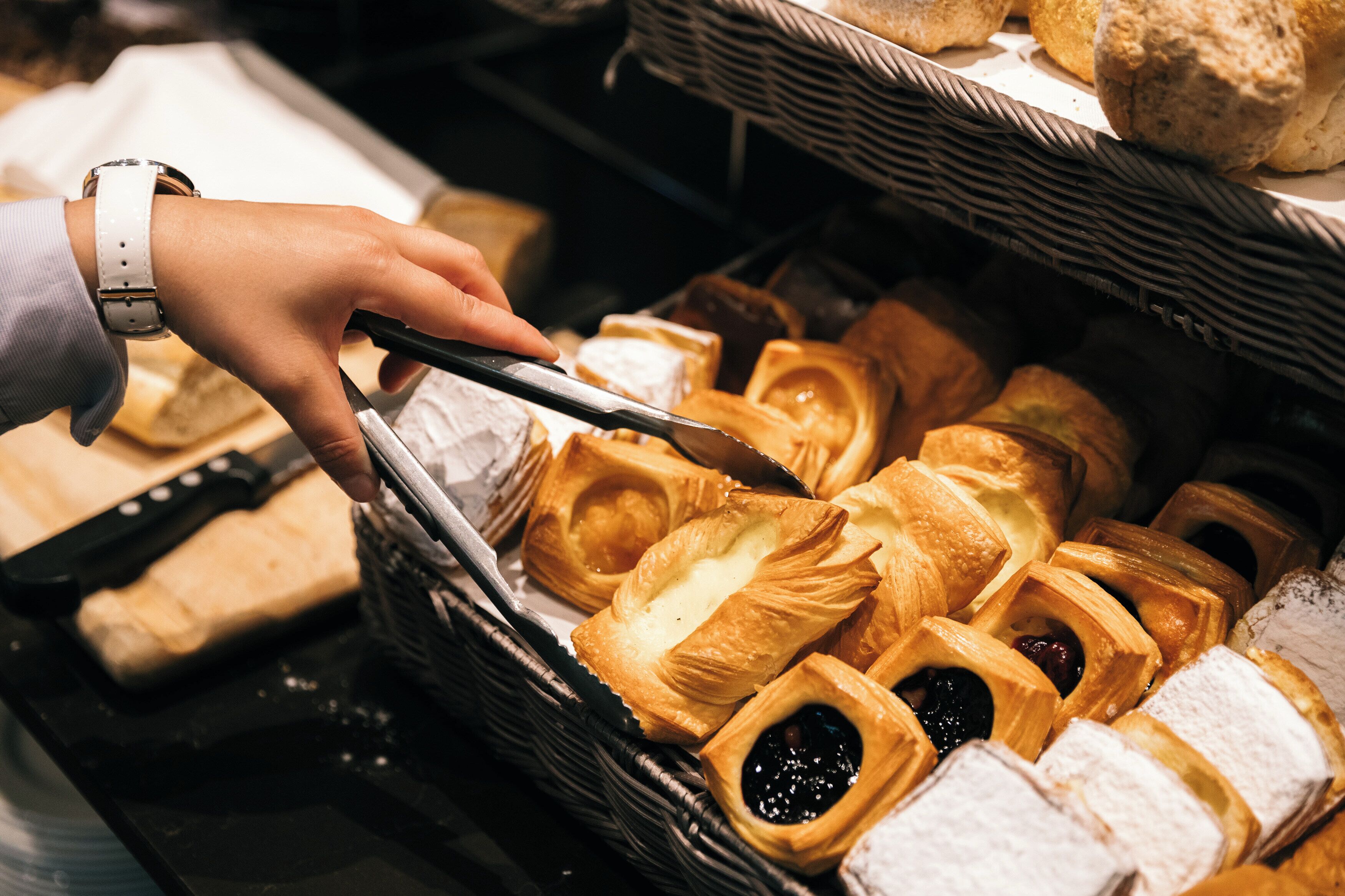 A hand selecting pastries from a basket.