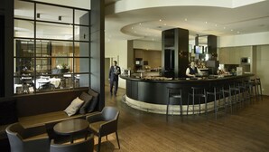 Un espace bar moderne doté d’un comptoir incurvé, de sièges et offrant une vue sur la salle à manger.