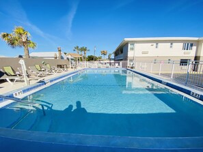 A swimming pool with a 4 ft depth marker, surrounded by lounge chairs and palm trees. - A1A Super Inn (Ormond Beach)