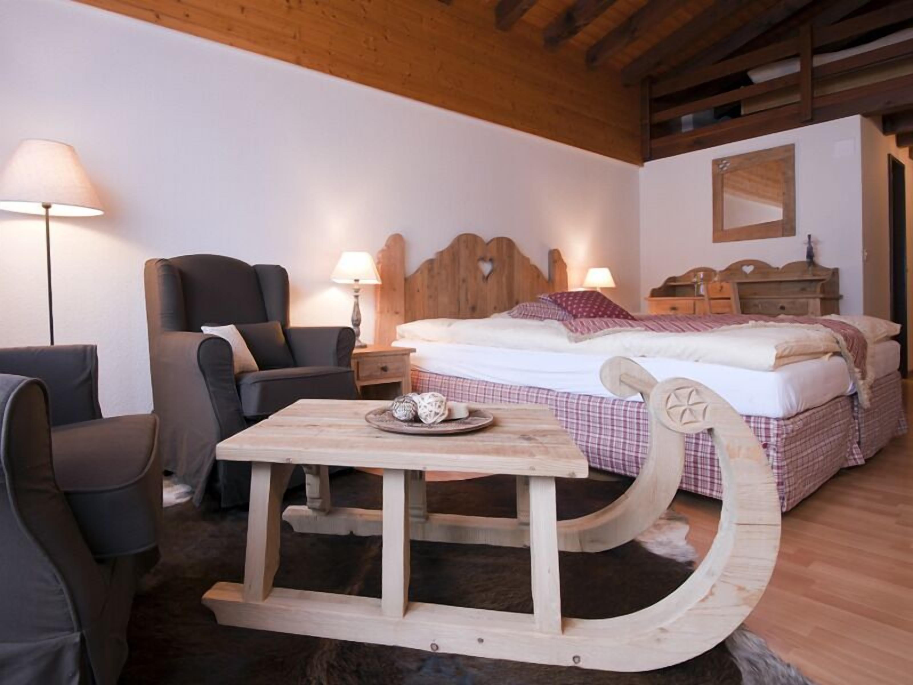 Una habitación acogedora con una cama de madera, una mesa de madera con una bandeja, una silla y una lámpara.